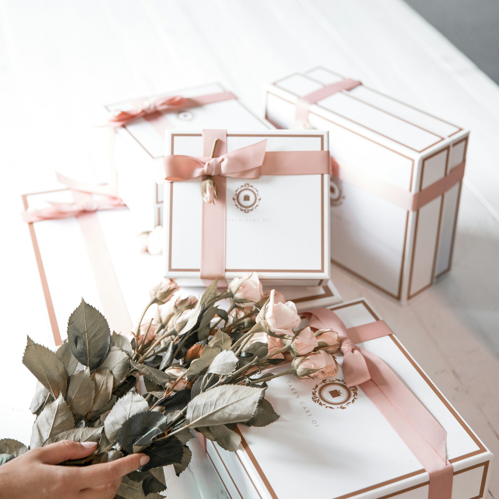 Real wrapped gift boxes with pale ribbon and flowers for an anniversary-style gift guide.